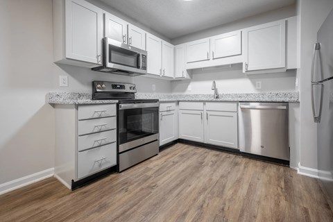 A kitchen with white cabinets and a wooden floor.