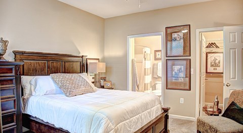 A bedroom with a large bed and a painting on the wall.