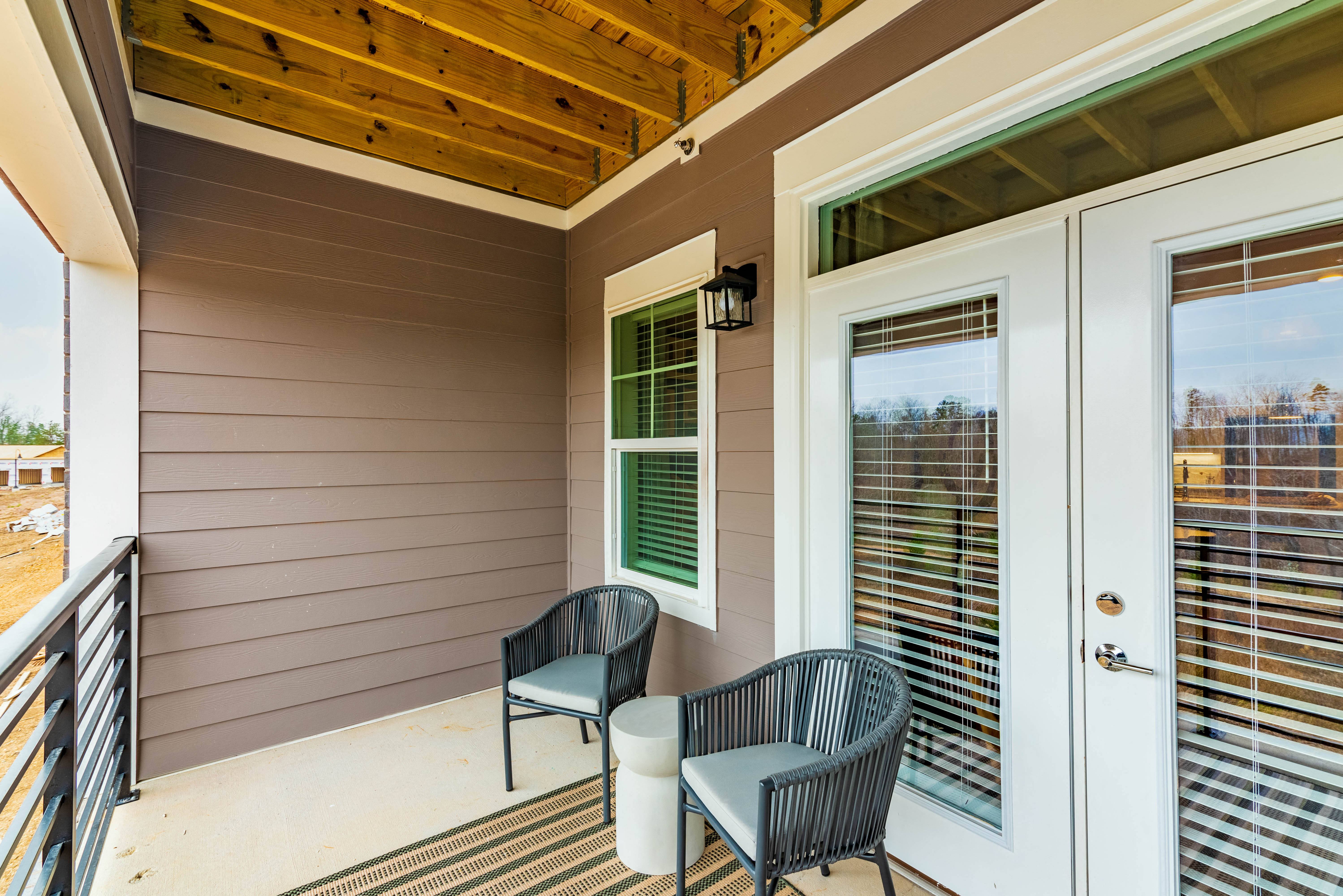 the front porch of a house with two chairs and a door