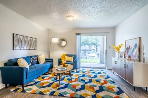 a living room with a blue couch and a colorful rug