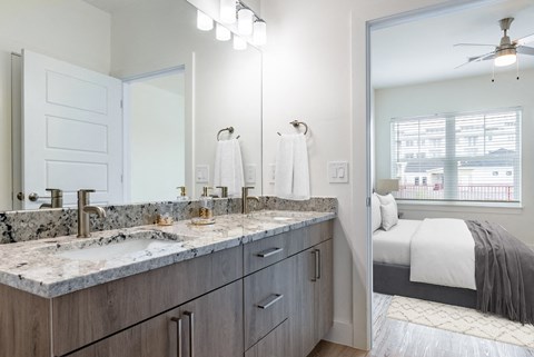 a bathroom with a sink and a mirror and a bedroom with a bed