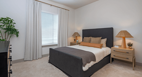 A bedroom with a large bed and two lamps.