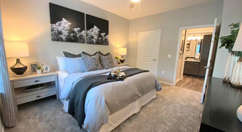 A bedroom with a large bed and a painting on the wall at Crossings at Pooler Apartments in Pooler, GA