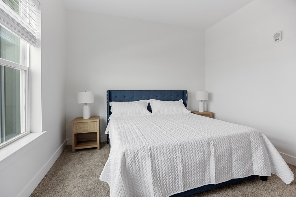 A Bed with a White Comforter and a Blue Headboard Plus Two Nightstands.