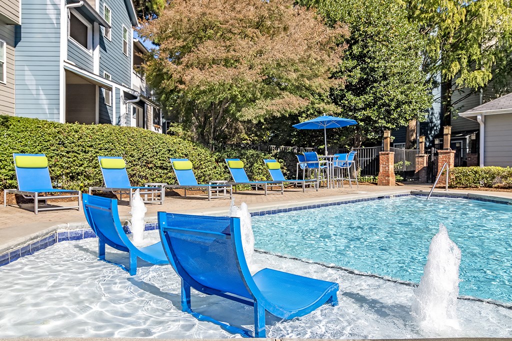 a swimming pool with blue chairs next to a house