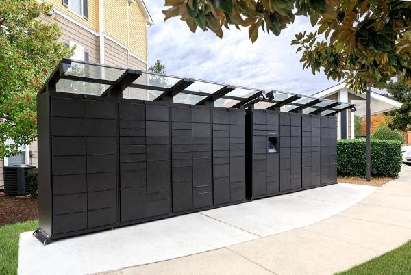 A black outdoor structure with a glass roof is situated on a concrete slab.