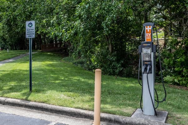 A charging station for electric vehicles is located next to a sign indicating the presence of a charging point.