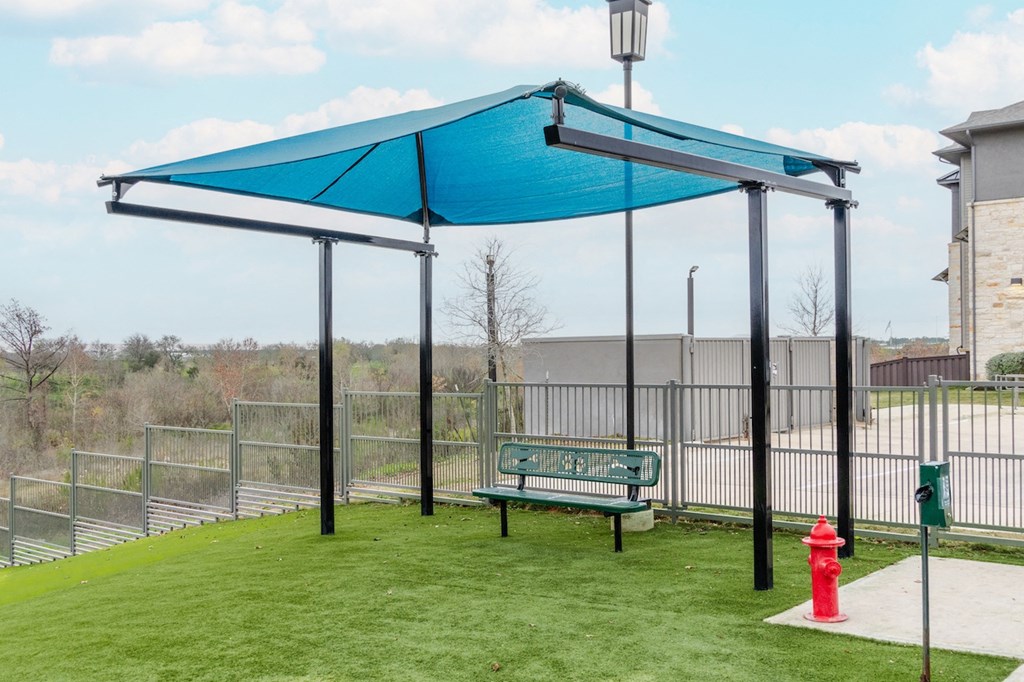 a park bench under a blue canopy with a fire hydrant