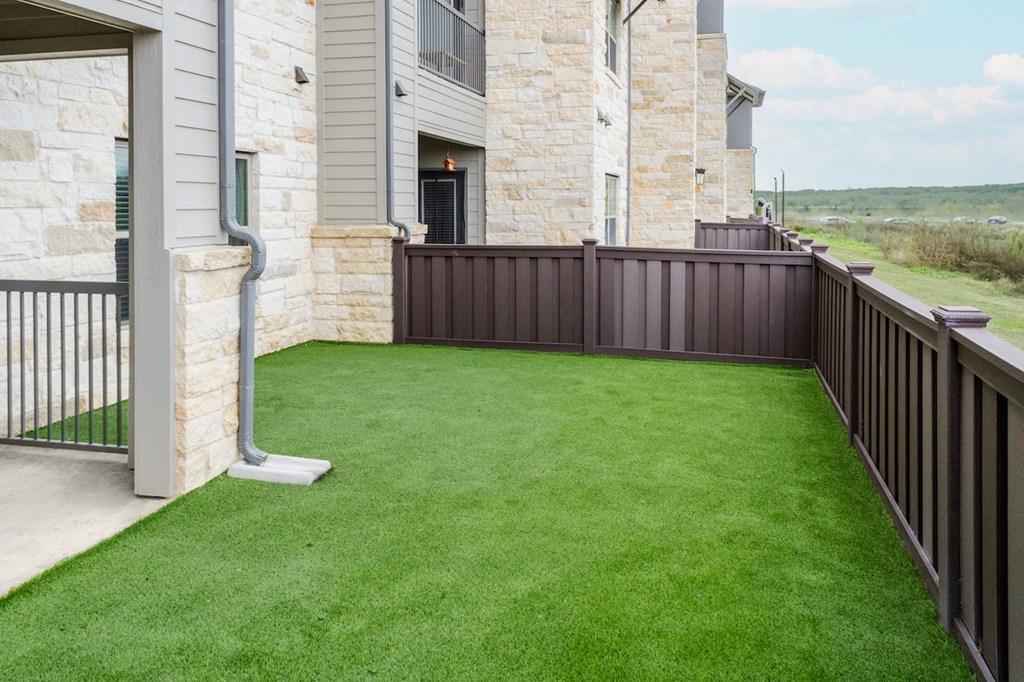 a yard with green grass and a house with a fence