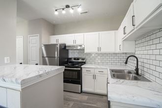 an empty kitchen with white cabinets and a stainless steel refrigerator