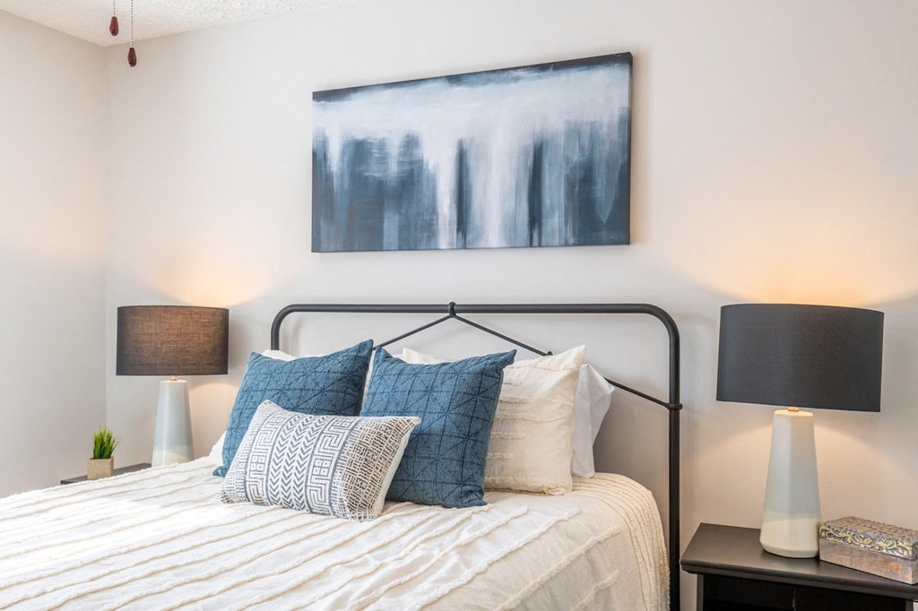 a bedroom with a bed with pillows and a painting on the wall