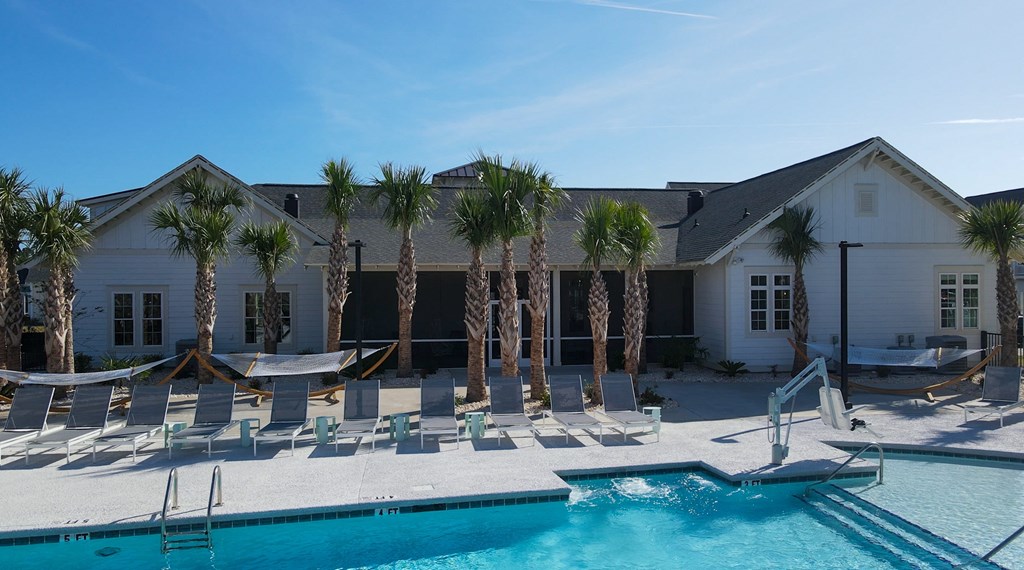 A pool area with lounge chairs and a building in the background.