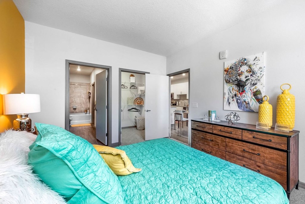 a bedroom with a bed and a dresser and a bathroom