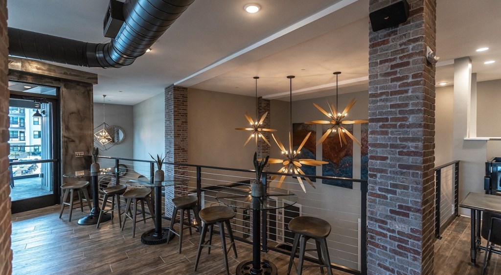 a bar with stools and tables in a room with a brick wall