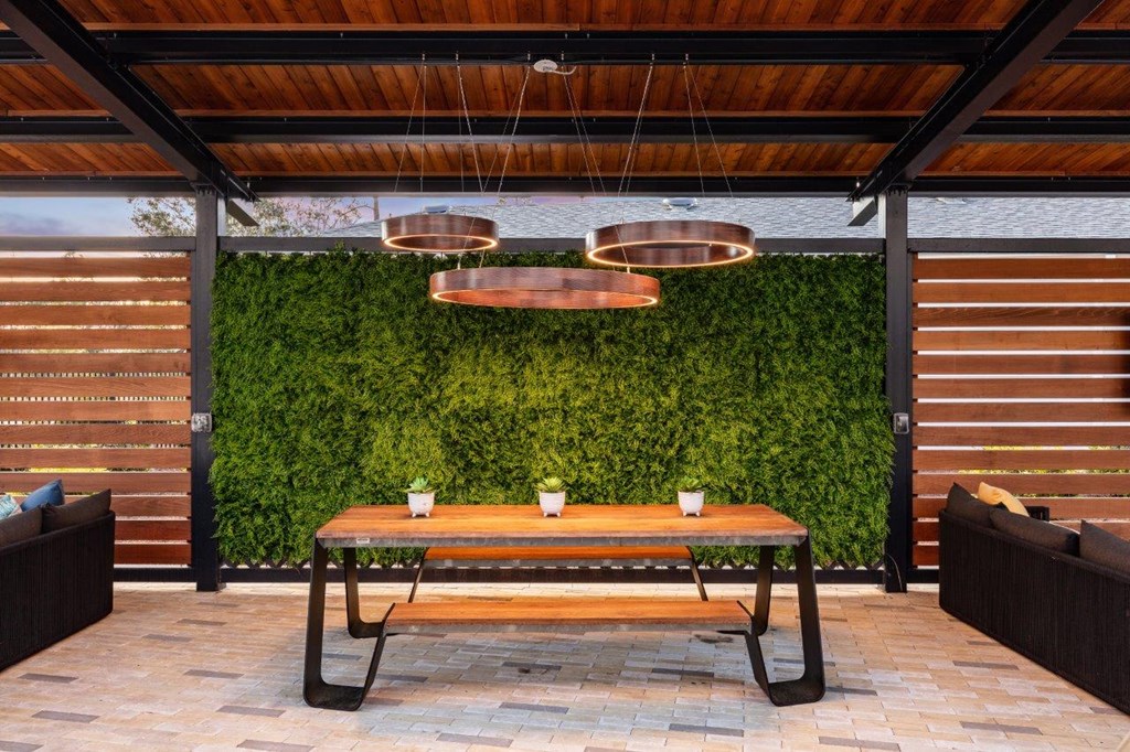 a patio with a table and a green wall
