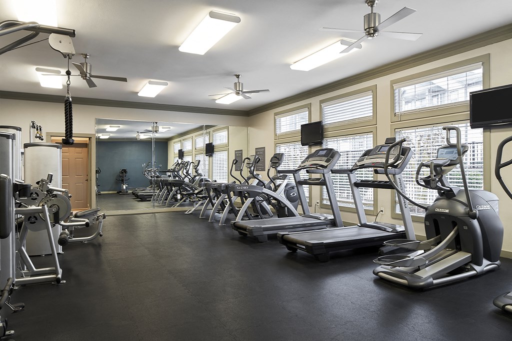 a gym with cardio equipment and weights on the floor