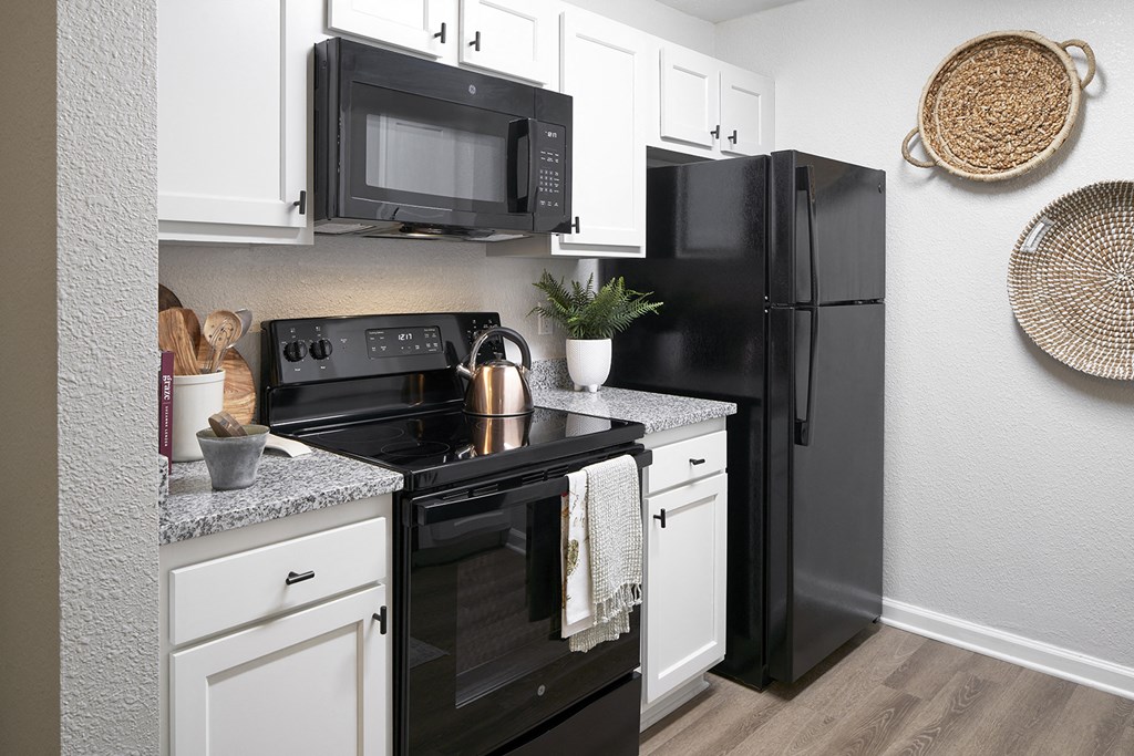 our apartments offer a kitchen with black appliances and white cabinets