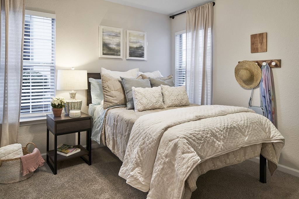 a bedroom with a large bed and two windows