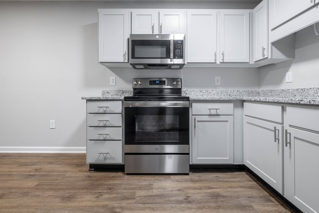 a kitchen with white cabinets and a stove and microwave