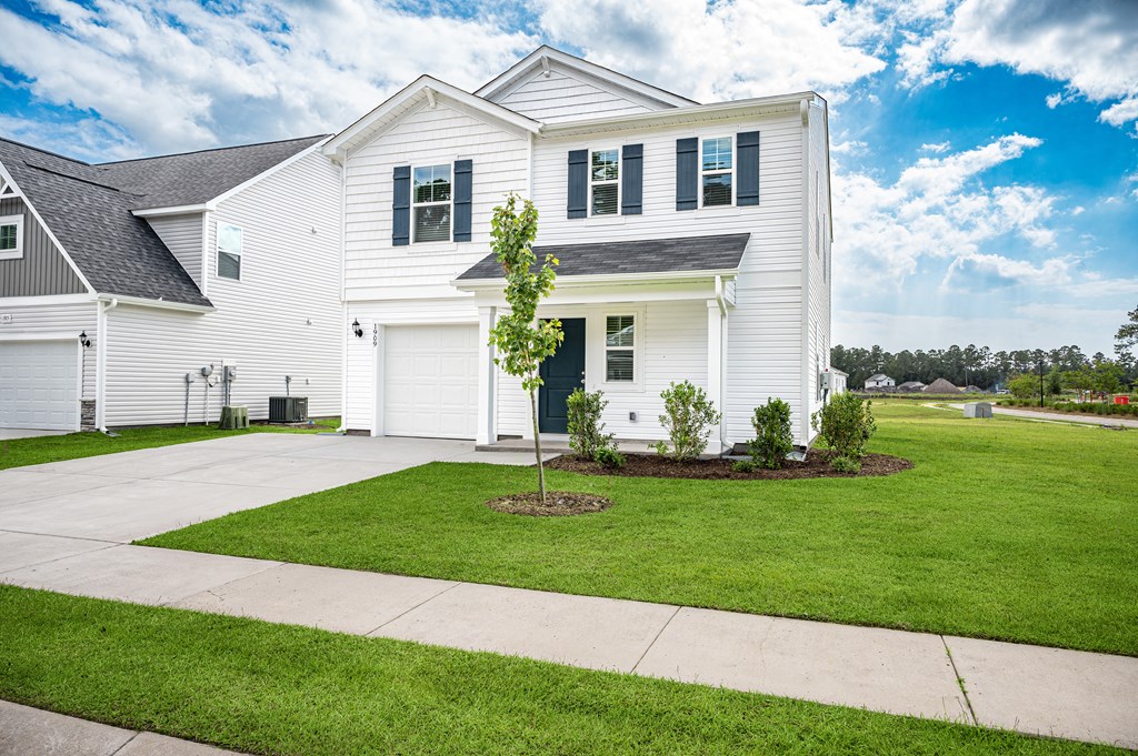 the front of a white house with a lawn and a driveway