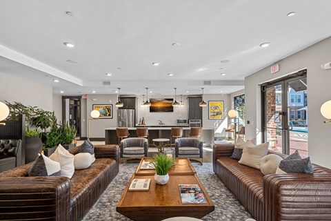 A large, well-lit room with brown leather couches and a wooden coffee table.