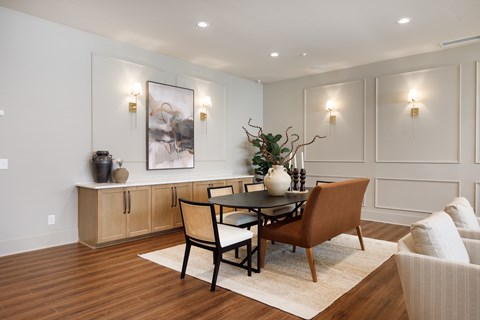 A dining room with a table set for two and a vase of flowers on the table.