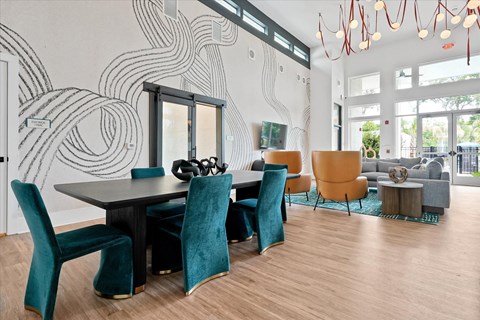 A modern dining room with a black table and blue chairs.