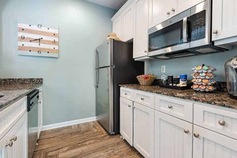 A kitchen with a black refrigerator and white cabinets.