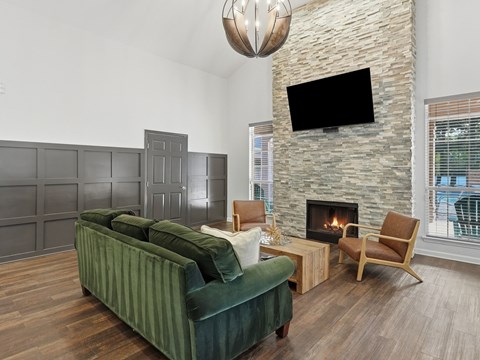 A living room with a green couch and a stone fireplace.