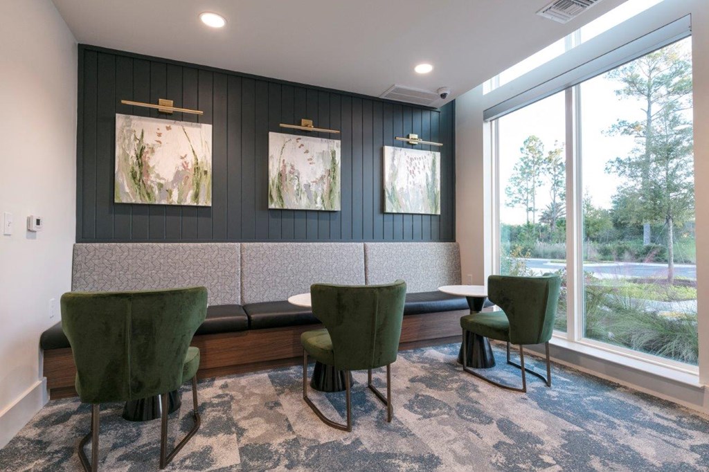 a lounge area with green chairs and a large window