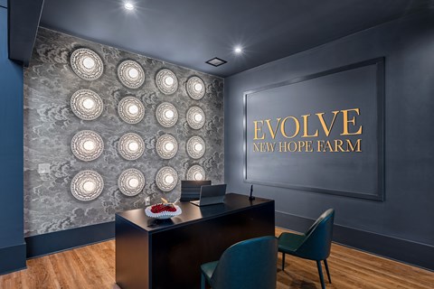 A conference room with a desk and chairs with a wall of lights and a sign that says