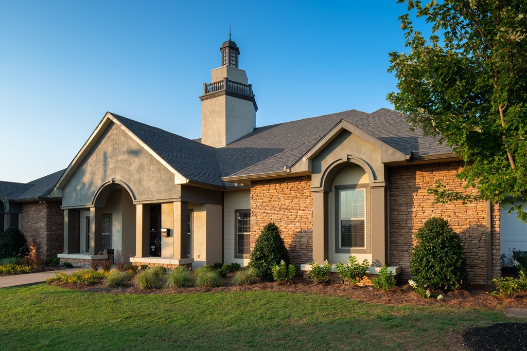 the front of a brick church with a lawn and a tree