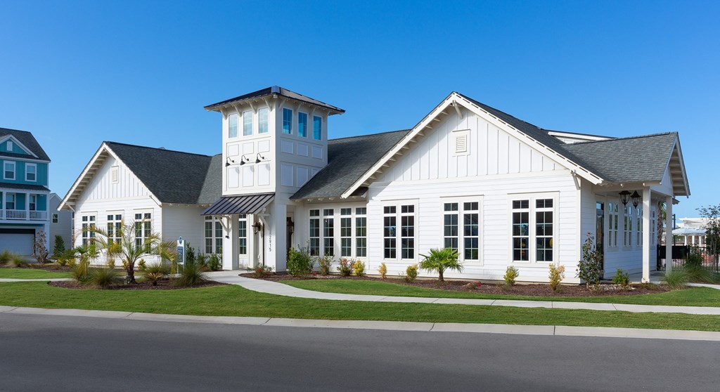 A white house with a black roof and a tower.