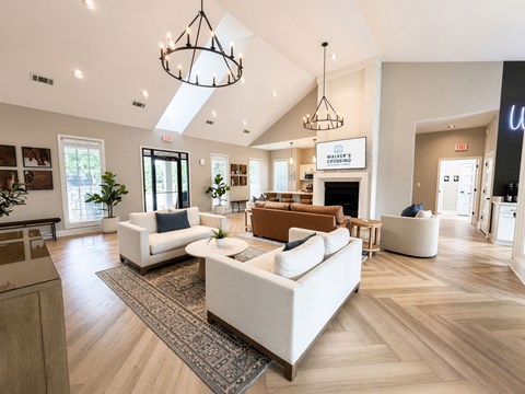 A spacious living room with a white sofa set and wooden flooring.