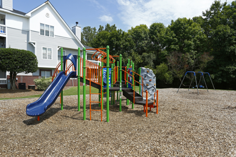 a playground with a slide and other toys in front of a house