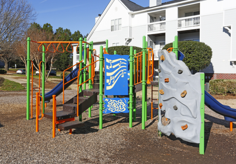 a playground with a slide and climbing equipment in front of a house