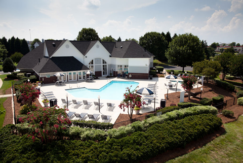 an aerial view of a pool with chairs and a building