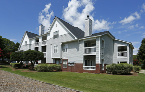 an apartment building with a lawn and a blue sky