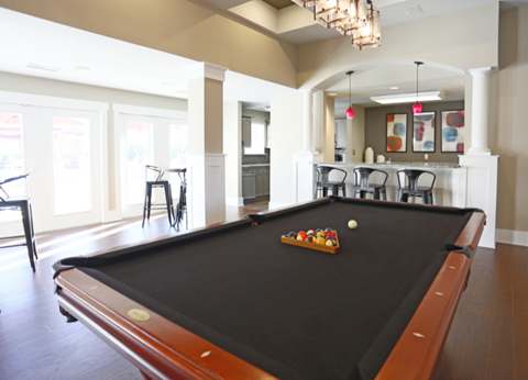 a pool table in a living room with a kitchen