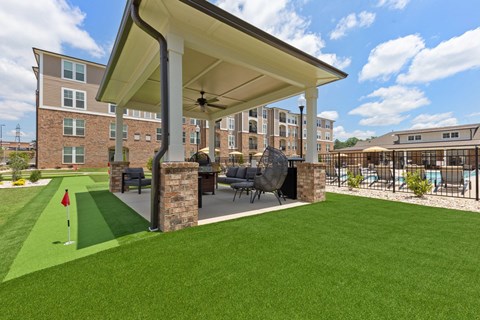a covered patio with a lawn and a building in the background