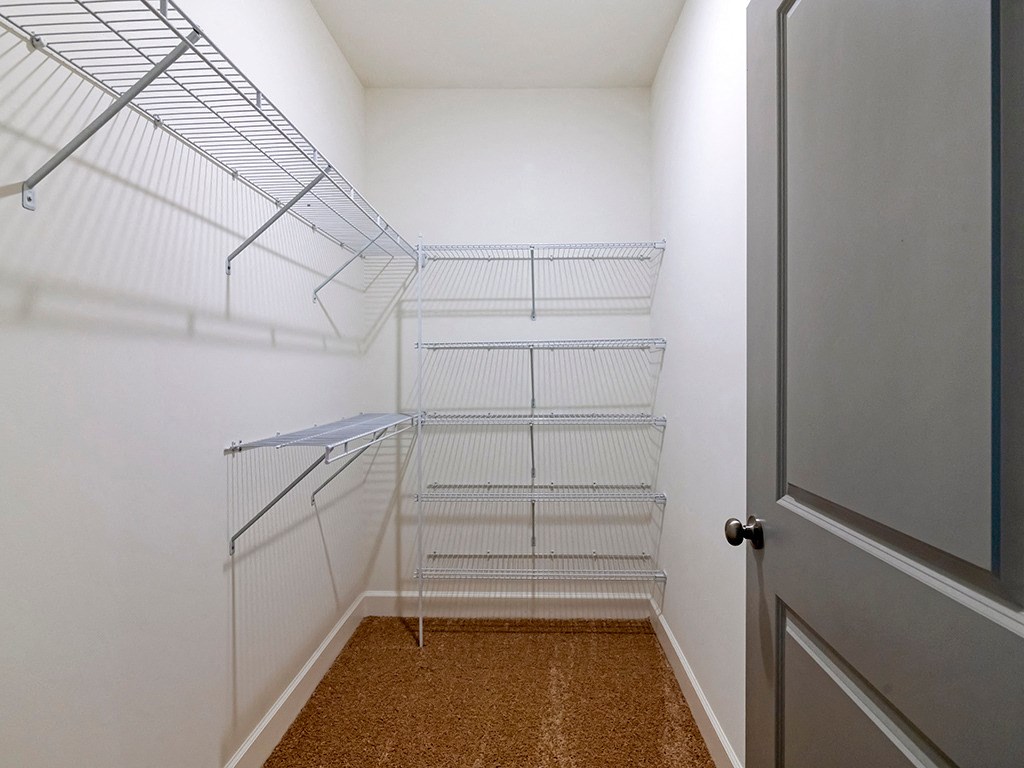 a walk in closet with white metal shelves and a door