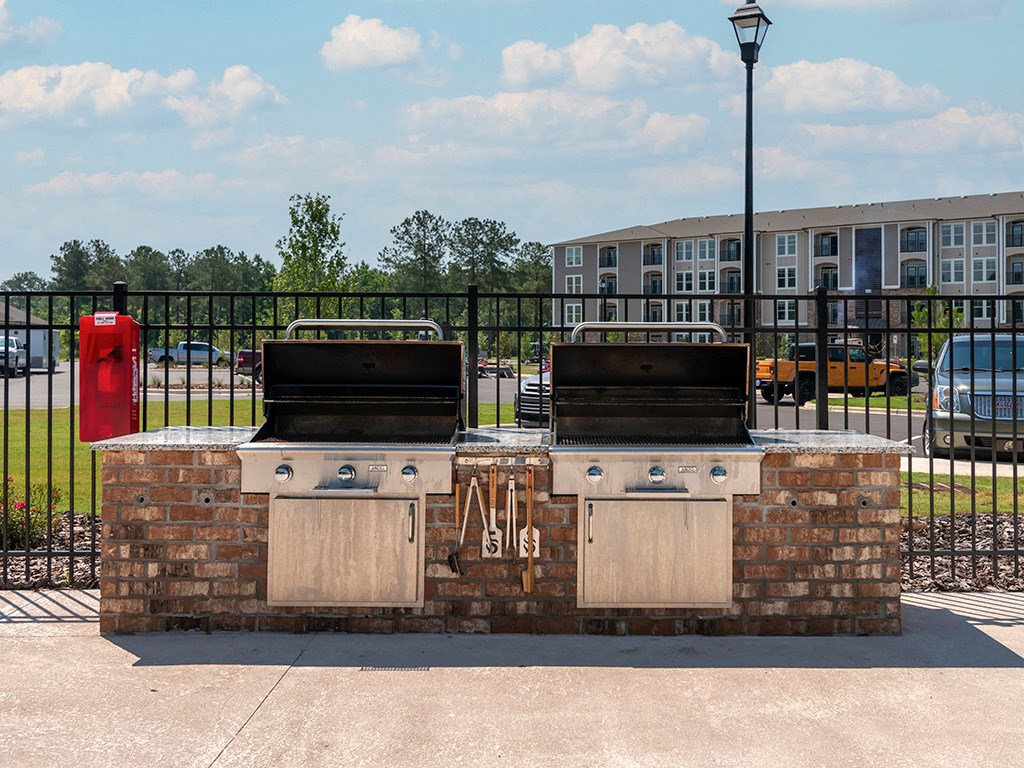 two bbq pits on a brick grill with a building in the background