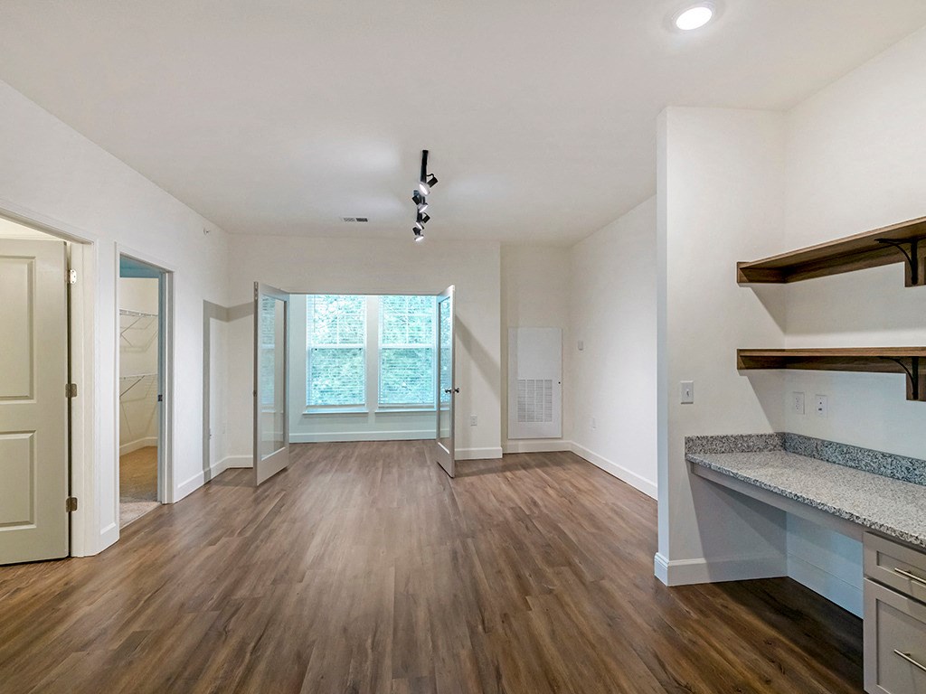an empty living room with wood flooring and a window
