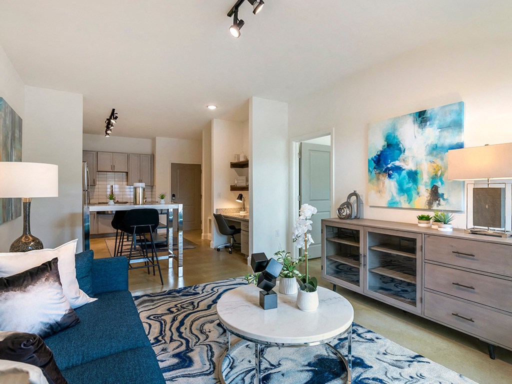 a living room with a couch and a coffee table and a kitchen with a table