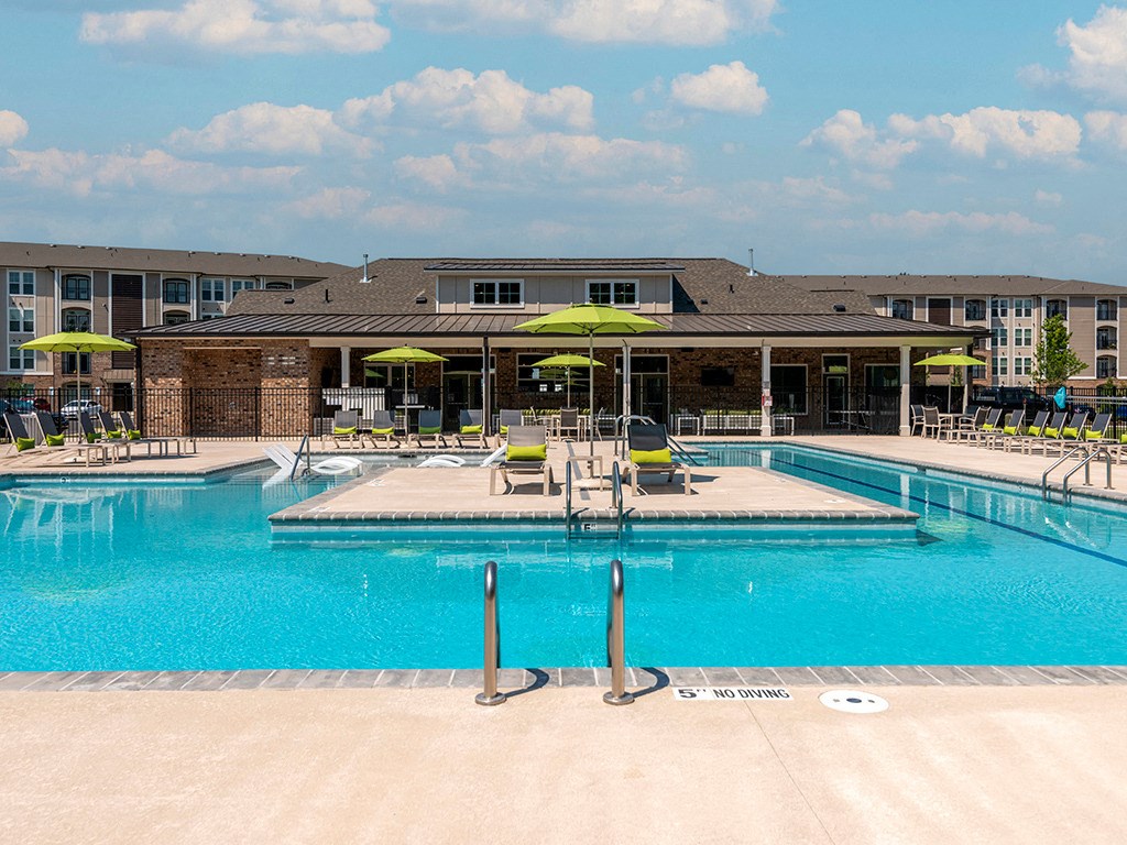 a swimming pool with chairs and umbrellas in front of a building
