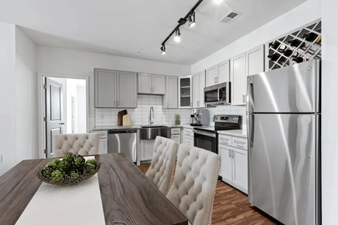 A modern kitchen with a wooden table and white chairs.