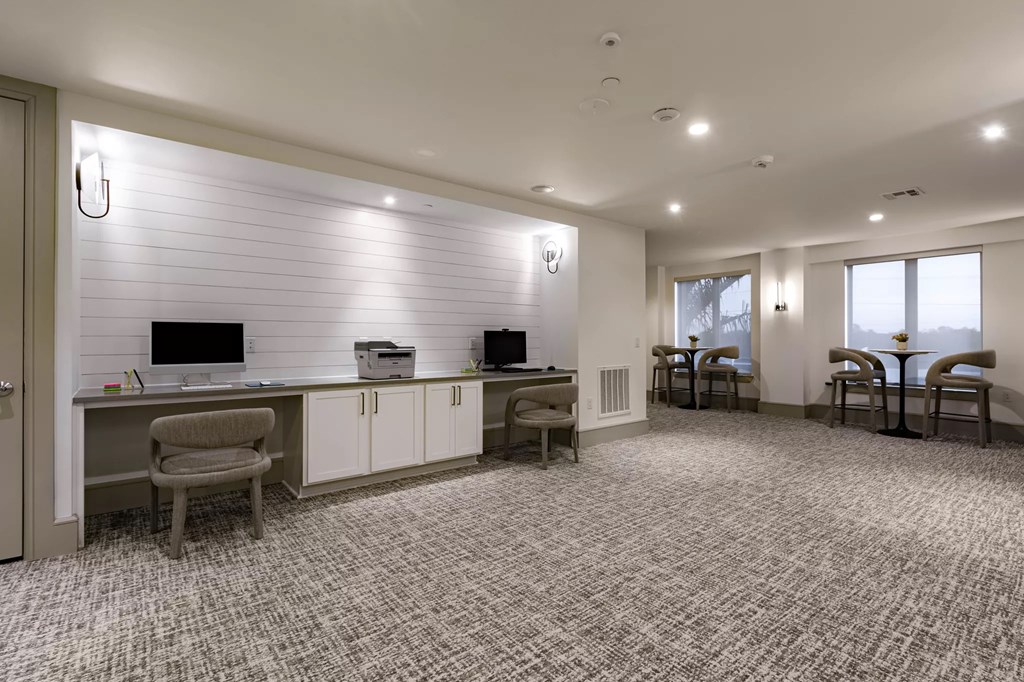 A room with a desk, chairs, and a computer.