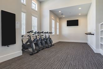 a fitness room with cardio exercise machines and a tv