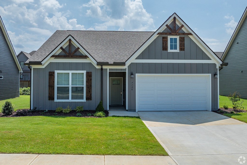 a gray house with a white garage door and a green lawn