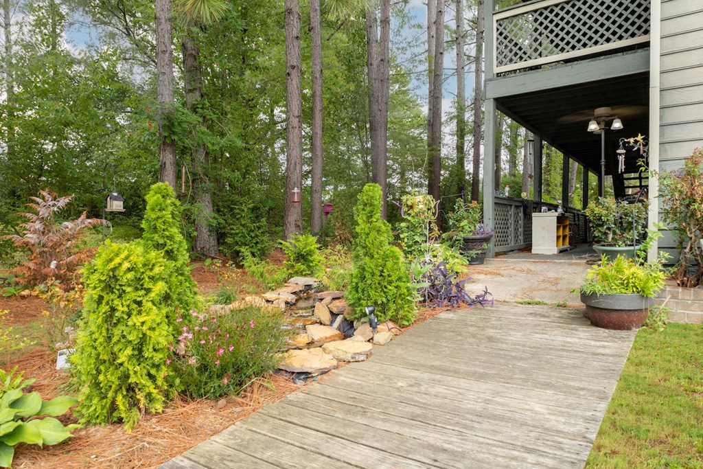 a wooden walkway in a garden with trees and plants